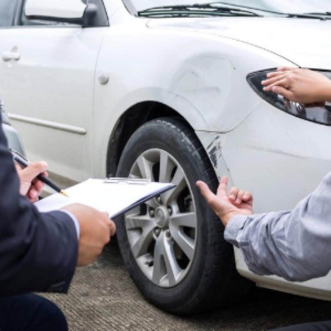 Technician inspecting damage on a silver car