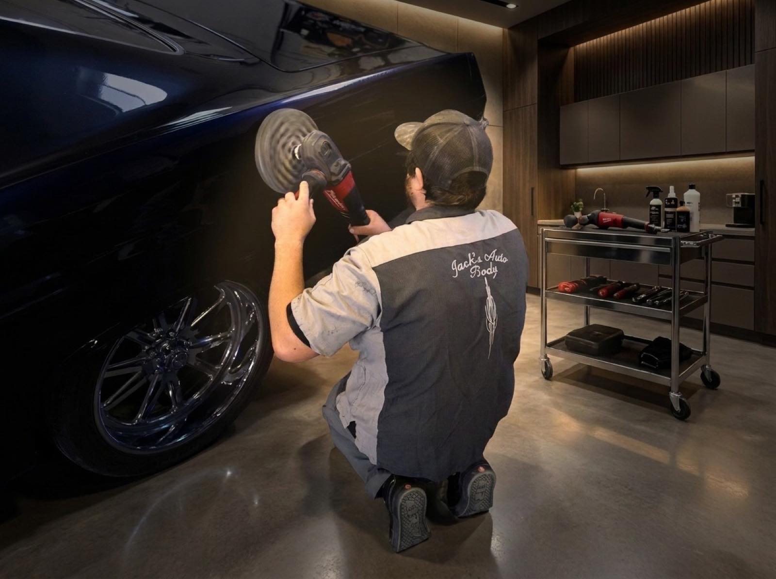 Jack's Auto Body technician machine-polishing a dark blue car
